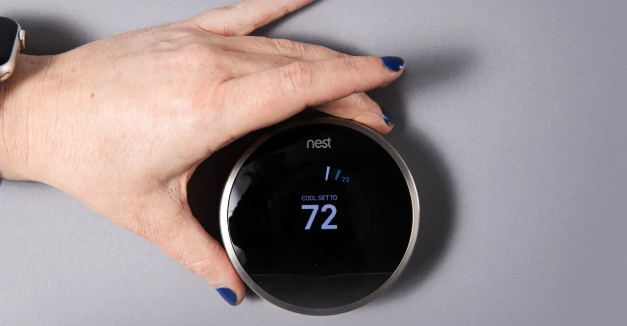 Mulher fazendo alongamento ao lado de um termostato Nest instalado na parede da sala