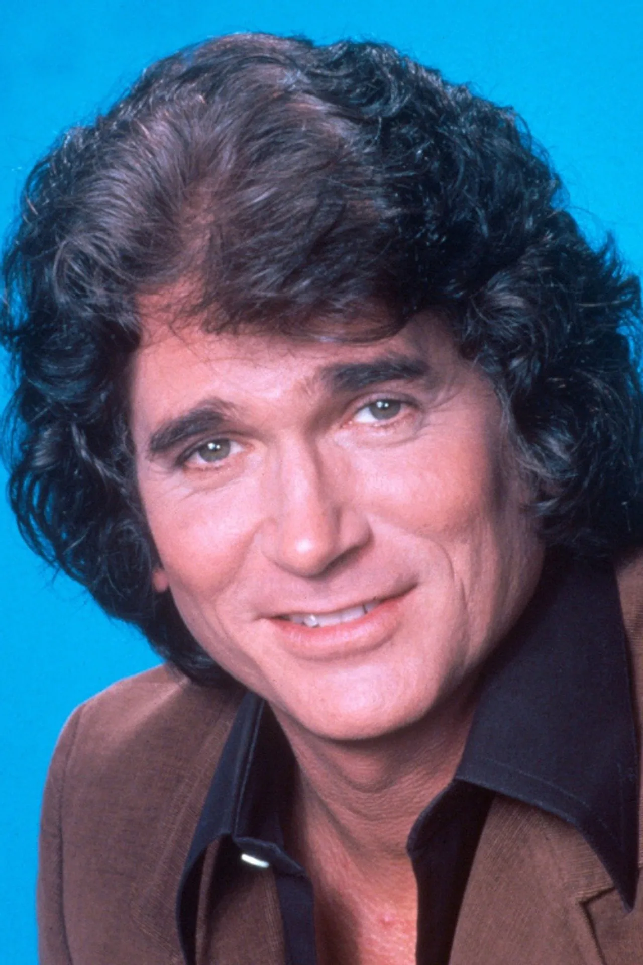 Michael Landon sorrindo enquanto segura um haltere ao lado de um bibelô de anjo
