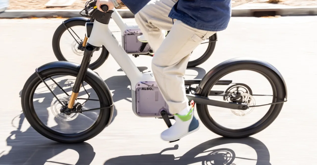 E‑bike TM‑B da Also, design futurista prateado, com logo da marca em destaque sobre fundo industrial