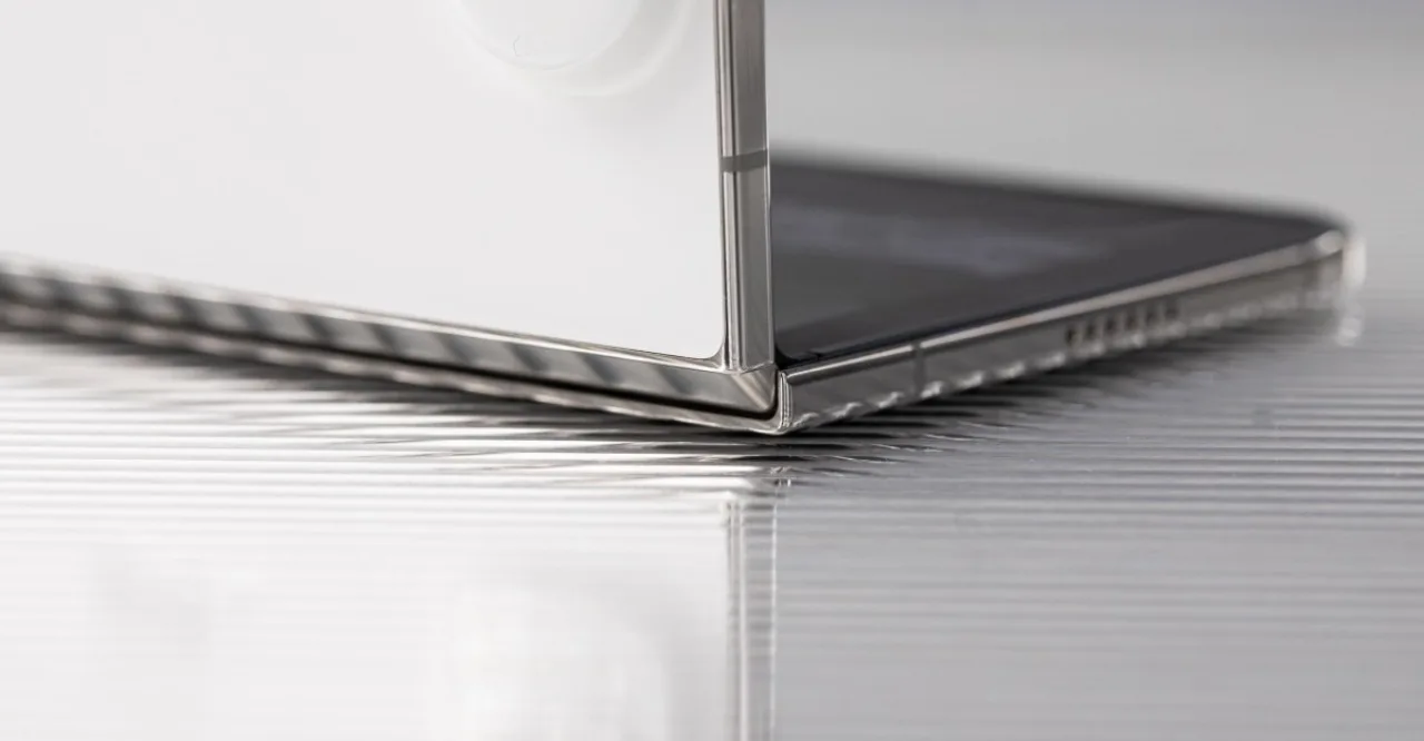 iPhone Duo aberto mostra linha luminosa atravessando a tela interna, com o logotipo da Apple ao fundo