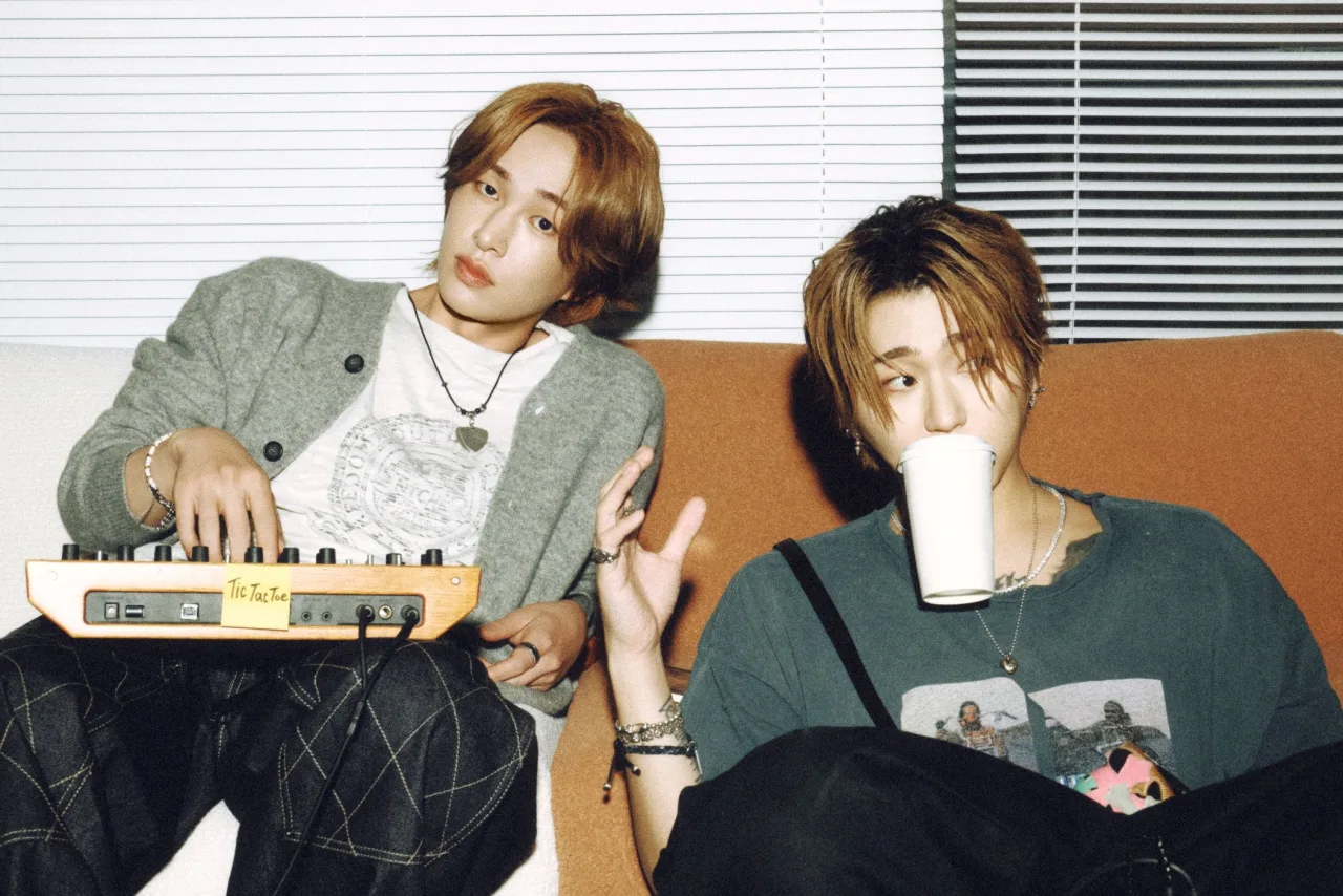 Onew e Zico seguram o troféu no palco iluminado do Music Core, ao fundo o logo do programa e luzes coloridas