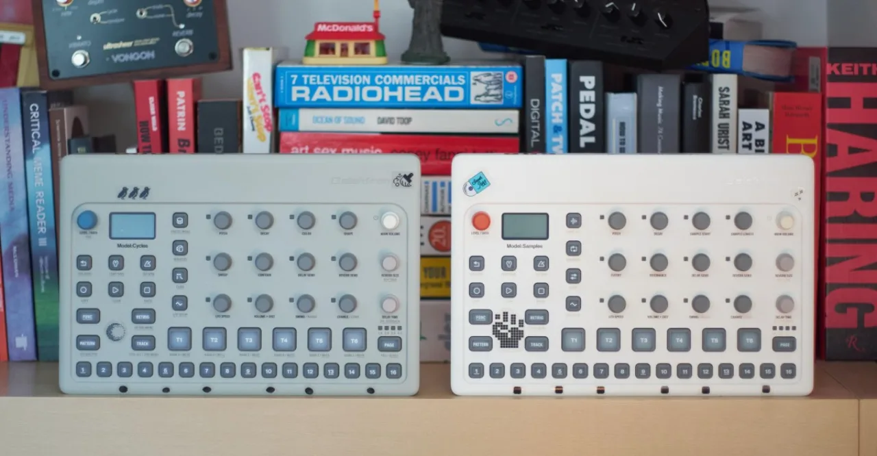 Um produtor sentado em frente a um laptop, rodeado por fones de ouvido, teclado MIDI e um copo de água