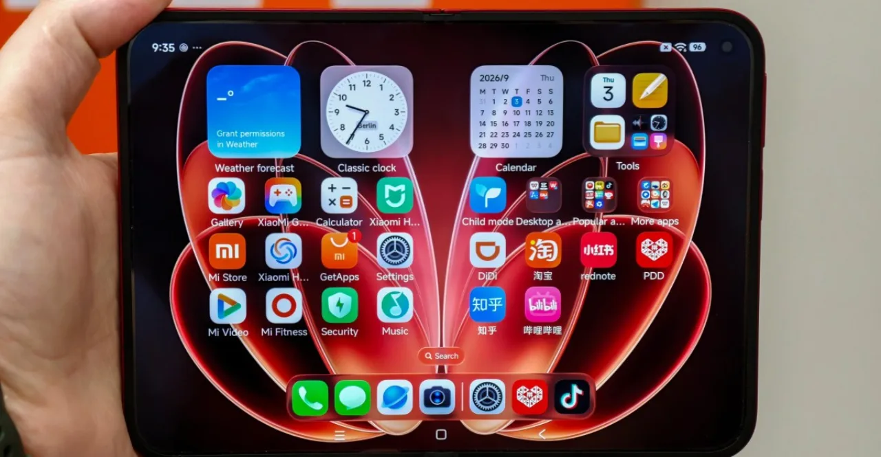 Jovem praticando alongamento, segurando o Xiaomi 18 Fold aberto, ao lado de garrafa d'água e smartwatch
