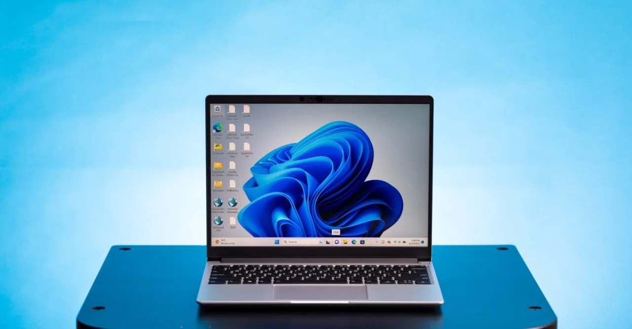 Jovem em roupa de academia, suando, segura laptop aberto mostrando tela azul ao lado de halteres