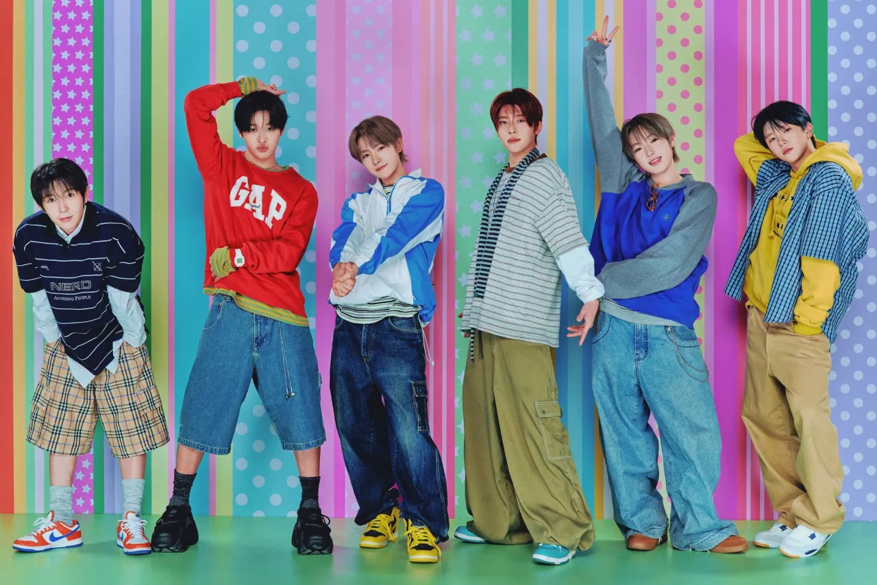 Membros de NCT WISH posam em trajes futuristas com o logo “I SPY” ao fundo, destacando o retorno em 12/10