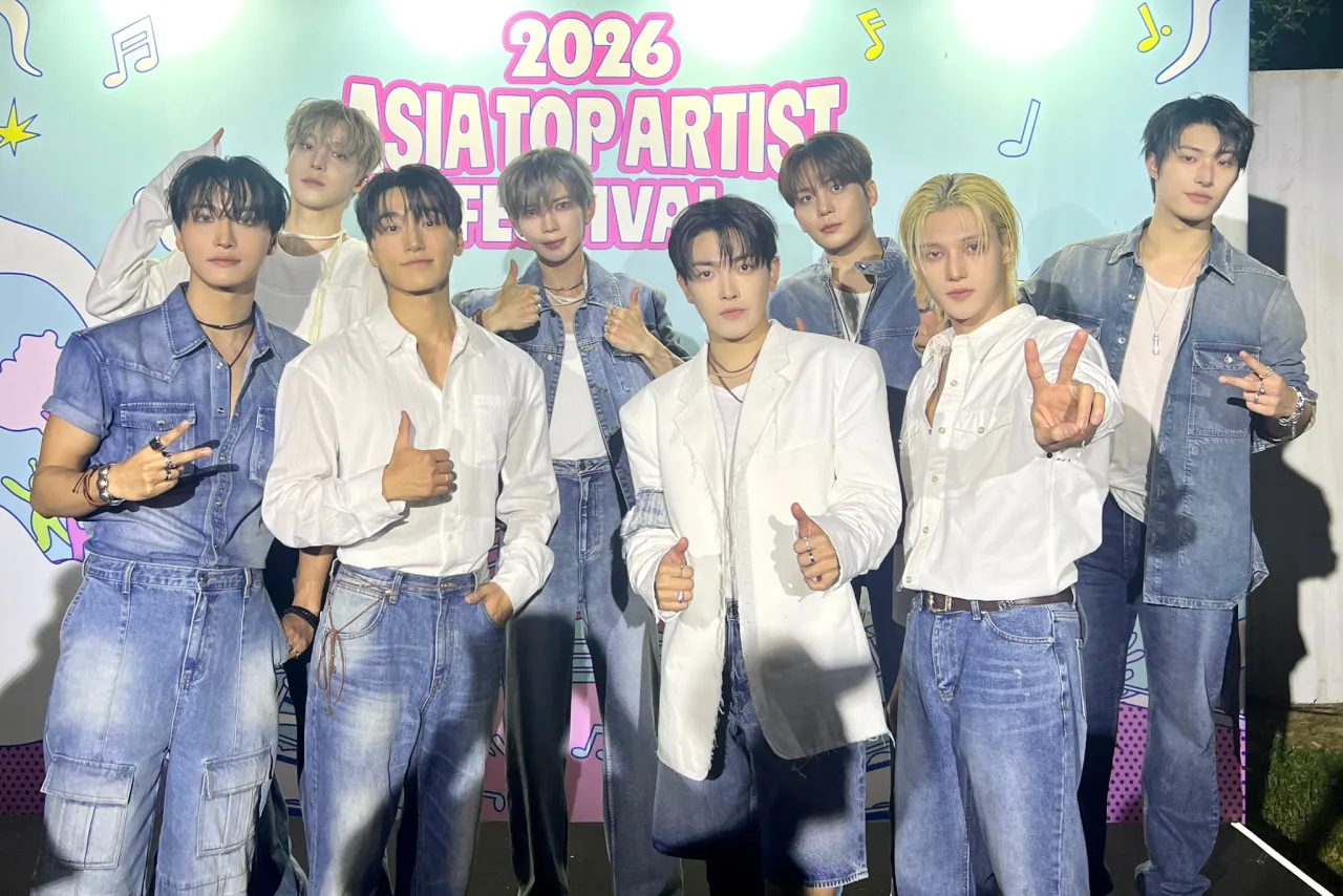 ATEEZ no palco do Inkigayo, iluminado, segurando o troféu enquanto o logo do programa brilha ao fundo