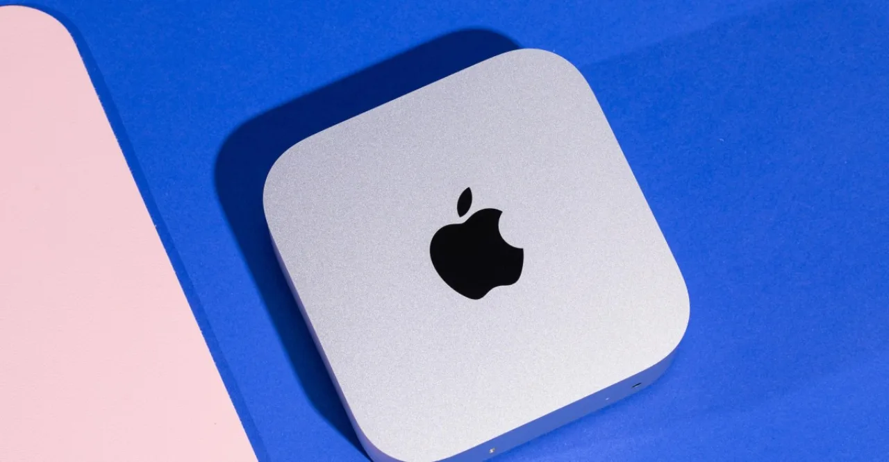 MacBook aberto exibindo alerta de permissão de disco ao lado de ícone de IA e logo da Apple