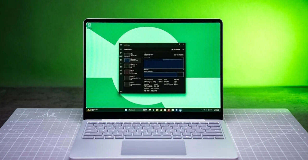 Jovem sentado em cadeira de escritório, segurando a cabeça, laptop aberto ao lado de um copo d'água