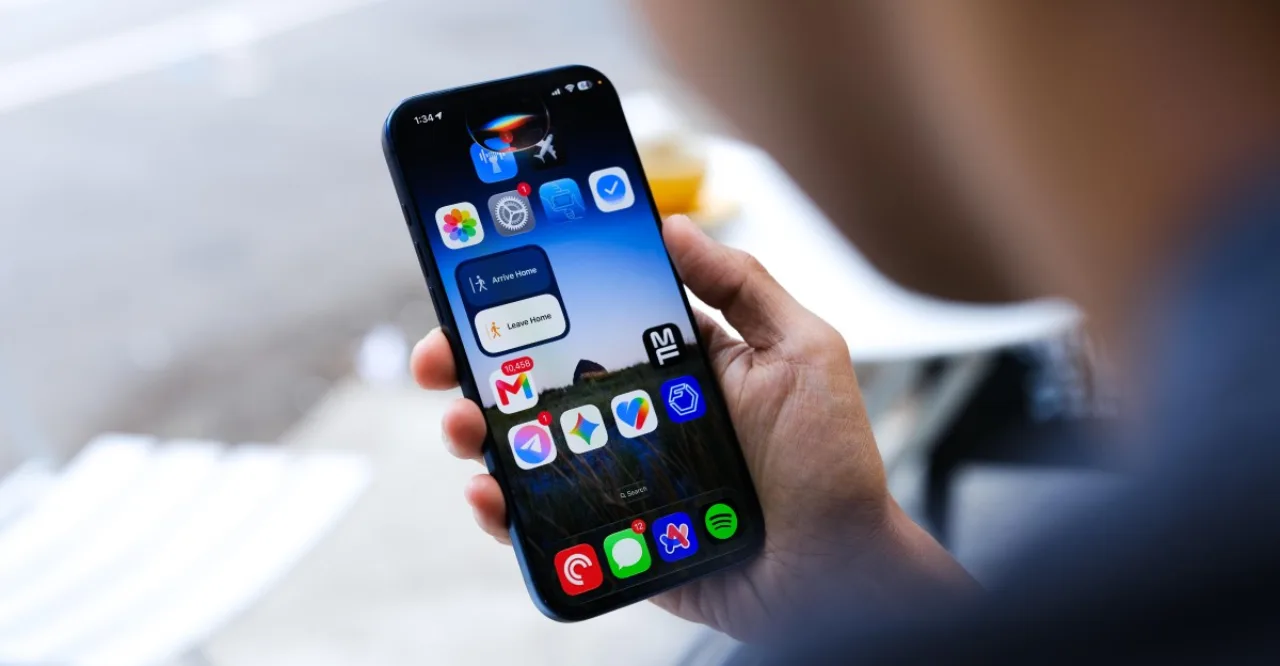 Pessoa correndo ao ar livre, usando fones Bluetooth e segurando um iPhone exibindo a nova Siri IA em tela