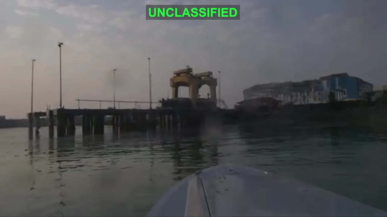 Atleta em traje de neoprene faz prancha sobre barco militar com drones explosivos ao fundo