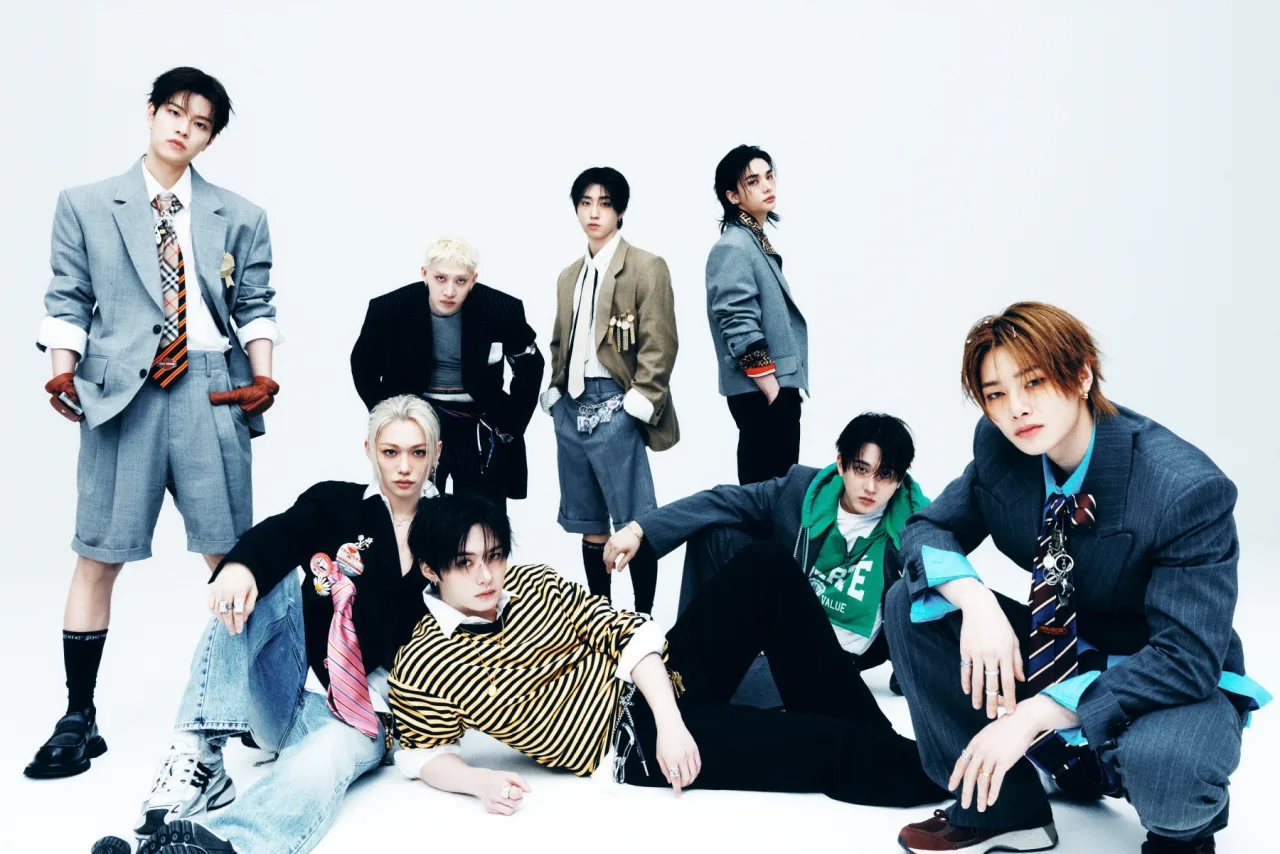 Jovem malhando com halteres, fones nos ouvidos, ao fundo a capa de 'THIS & THAT' da Stray Kids