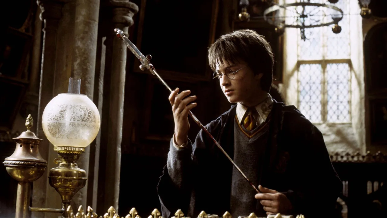 Jovem em roupa de bruxo faz agachamento com barra de ferro decorada com símbolos de Hogwarts