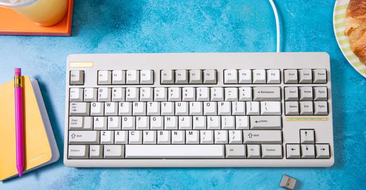 Um jovem em roupas de academia, sentado numa cadeira ergonômica, digitando em um teclado retro TKL enquanto segura uma garrafa de água