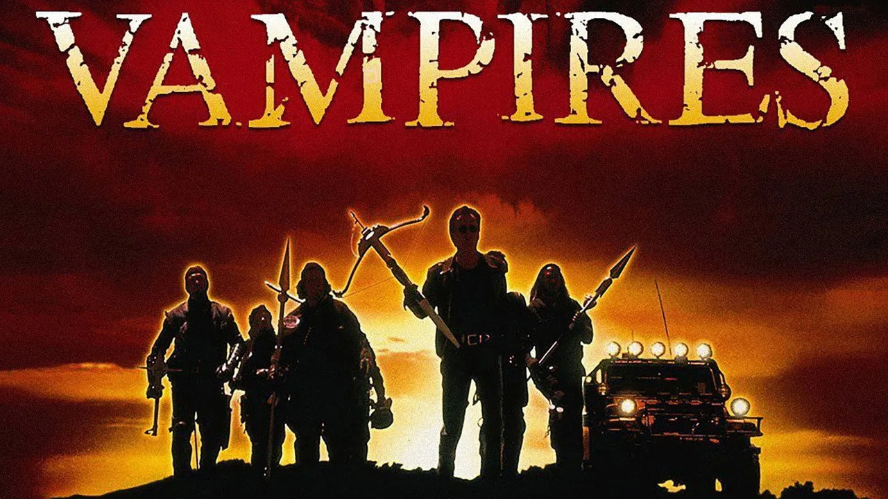 Diretor sentado em cadeira de cinema, segurando halteres, com pôster de Ghosts of Mars ao fundo