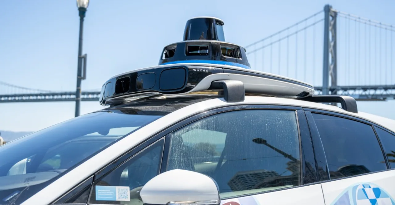 Corredor usando smartwatch, passando ao lado de um carro autônomo branco estacionado em rua urbana