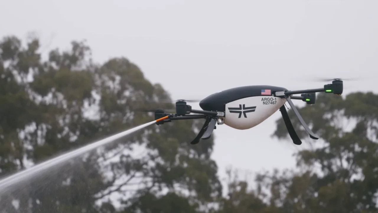 Drone sobre floresta em chamas, carregando tanque de água e jatos de retardante, com fumaça densa ao fundo