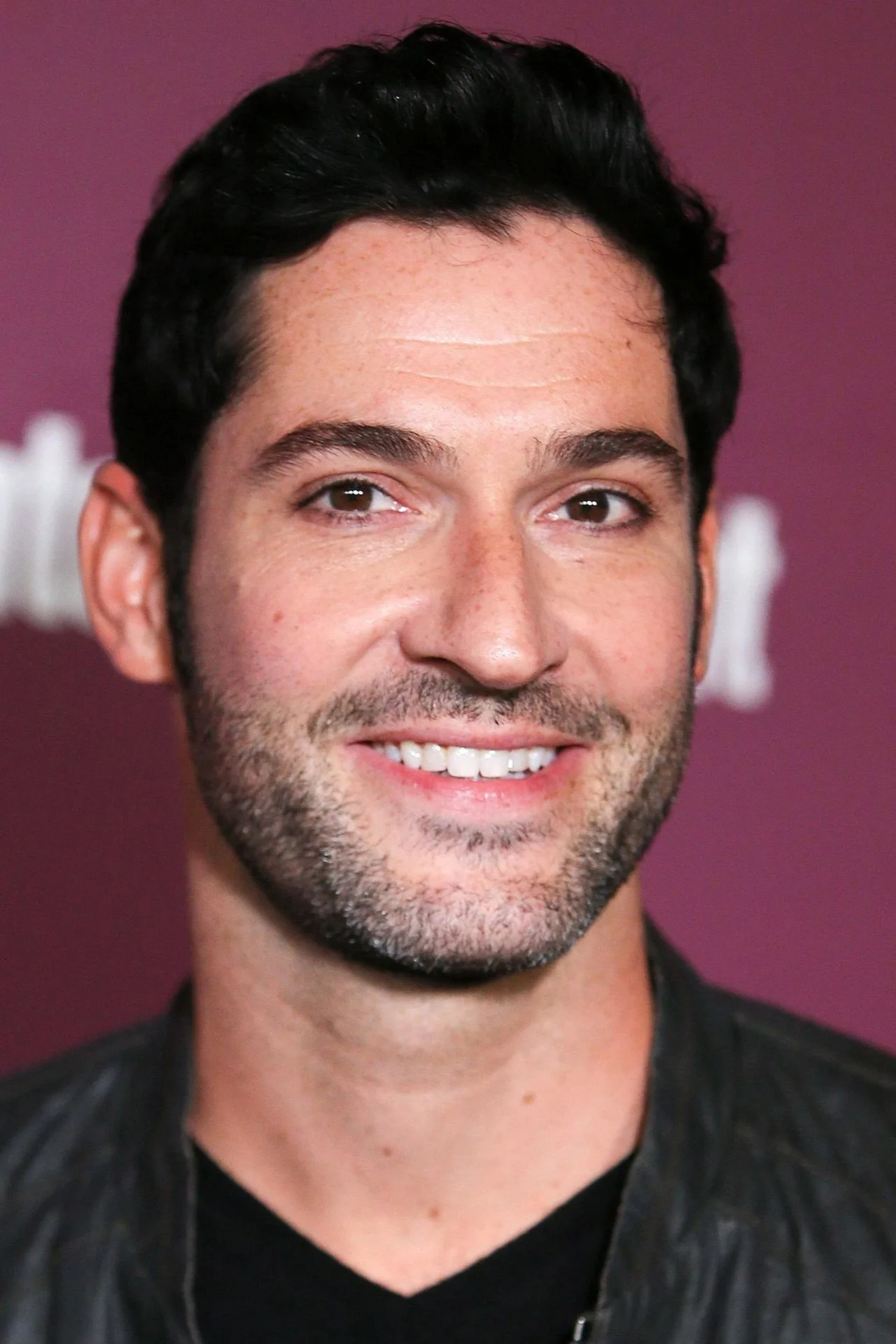 Tom Ellis executa barras fixas com colete de peso, exibindo físico definido ao lado de uma garrafa de água e halteres