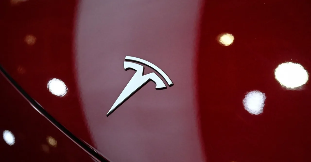 Homem de 40 anos vestindo roupa esportiva, smartwatch no pulso, ao lado de um Tesla Model 3 estacionado