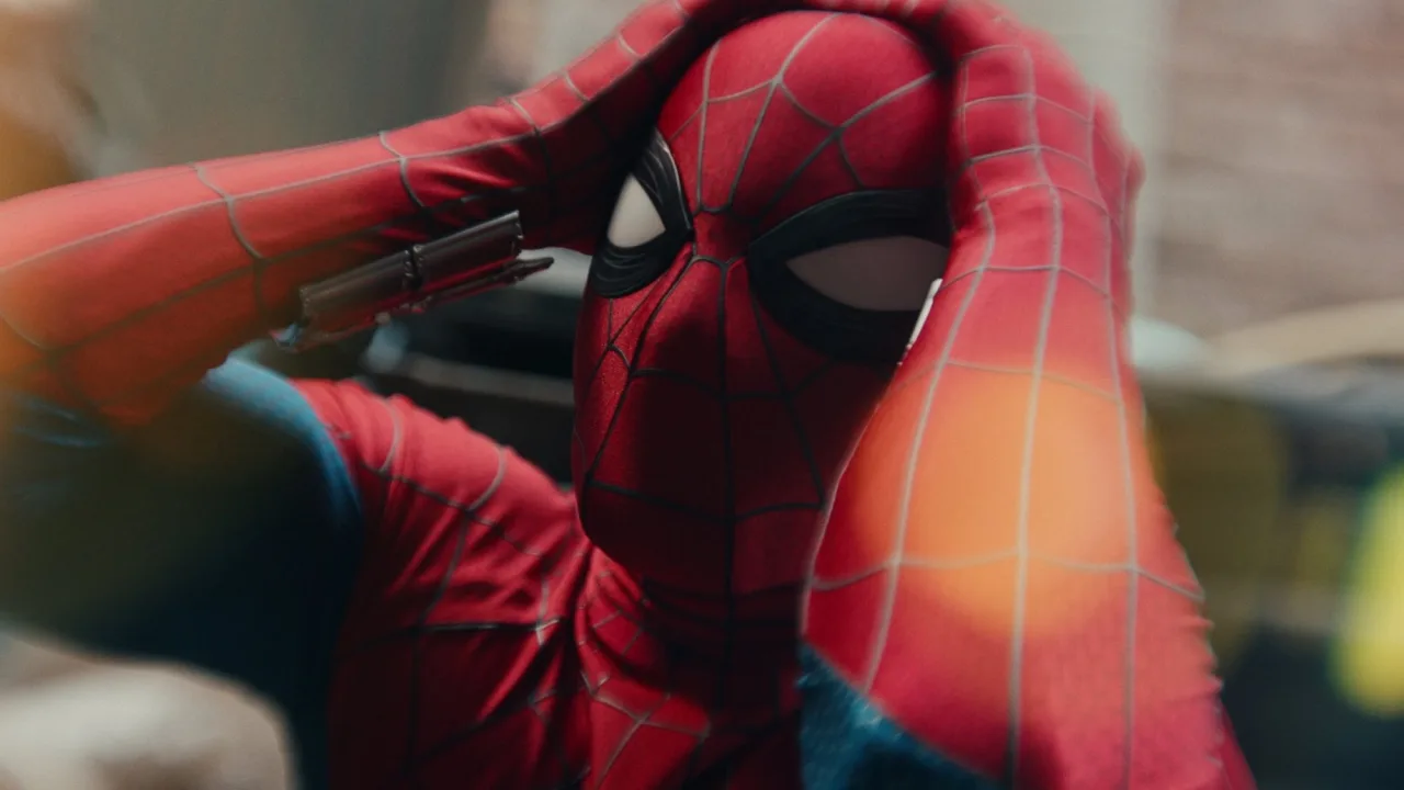 Jovem vestindo camiseta do Homem-Aranha faz flexão na academia, segurando barra com halteres ao fundo