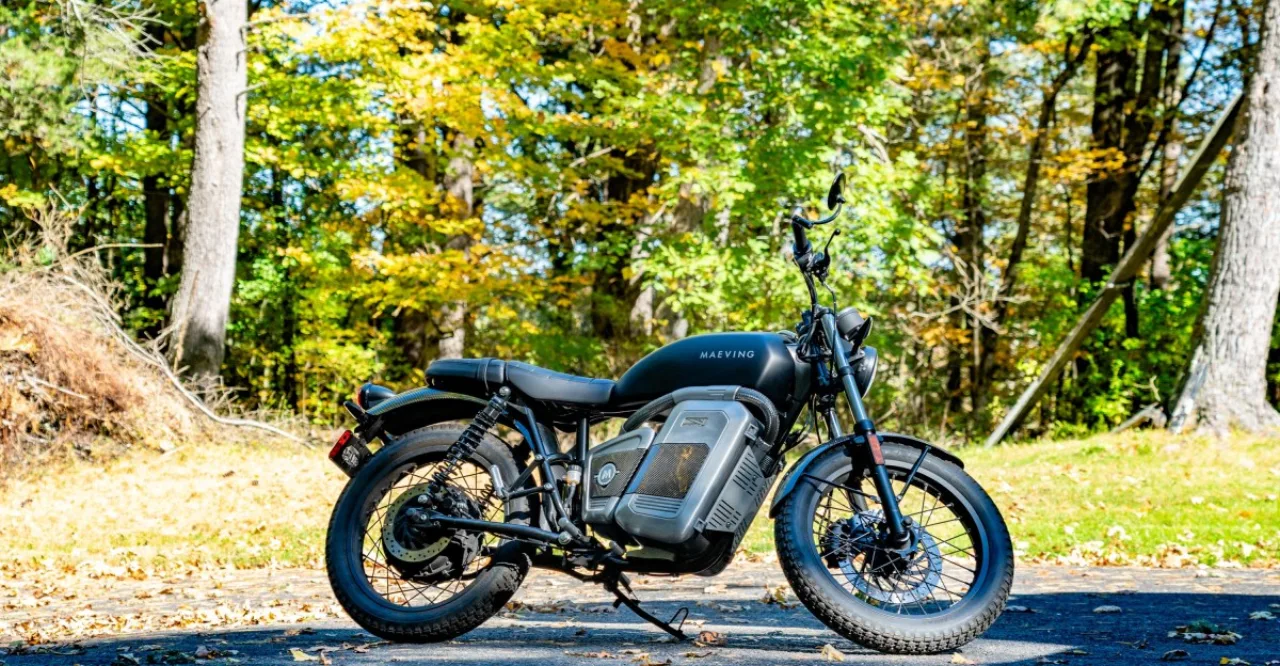 Scooter elétrico Maeving RM2 em destaque, com design premium, linhas agressivas e logo da marca ao fundo