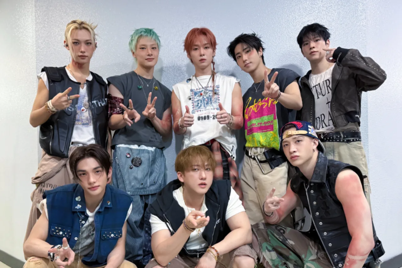 Membros do Stray Kids ensaiando coreografia intensa, suor visível, tênis de corrida e garrafas d'água no palco
