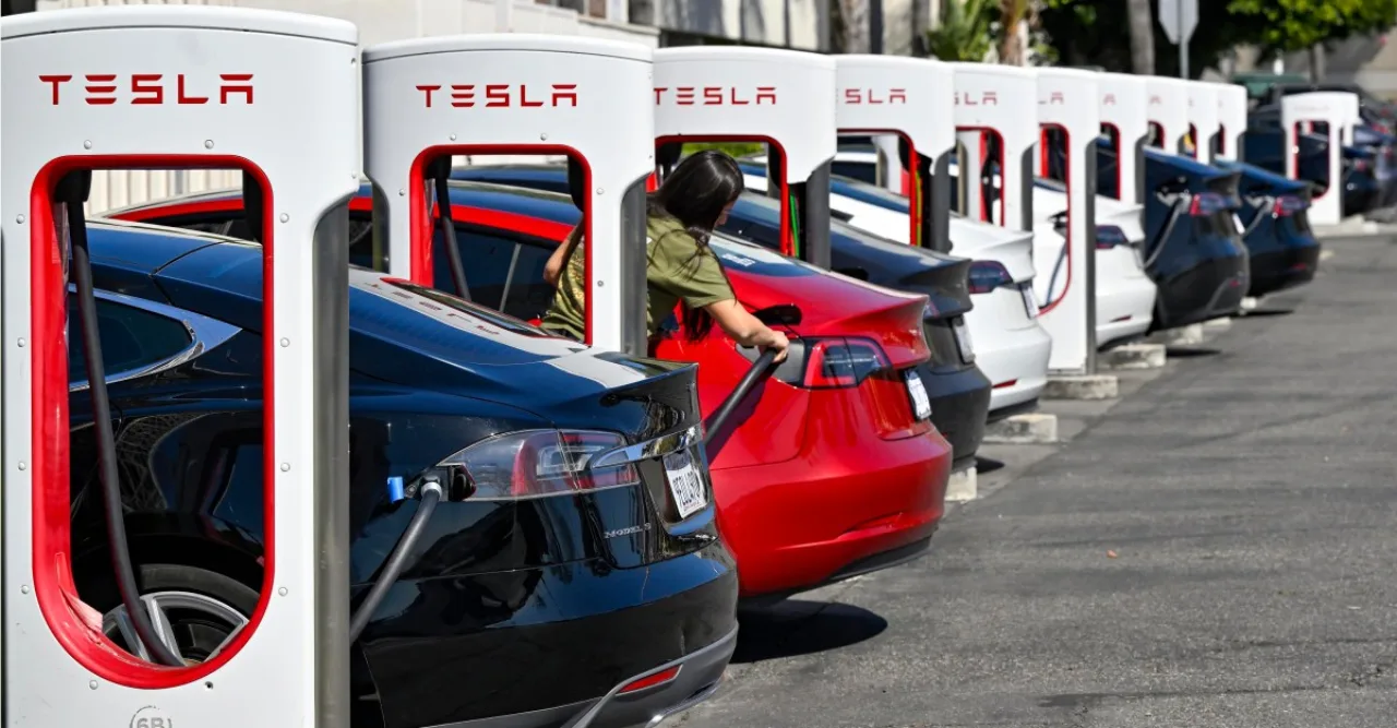 Tesla Model 3 estacionado em Supercharger, motorista saindo do carro com o cabo ainda conectado