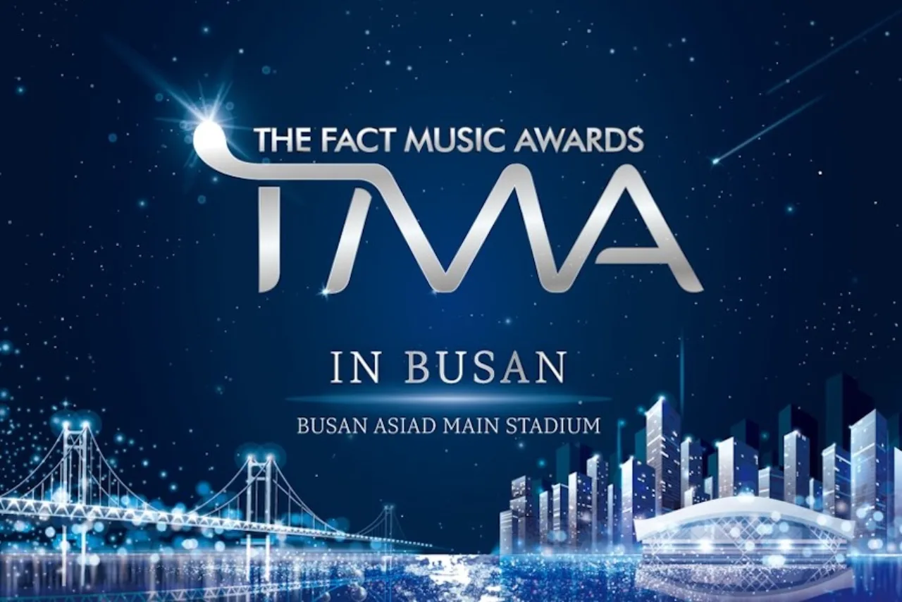 ATEEZ no palco da cerimônia em Busan, segurando o troféu Daesang enquanto o logo The Fact Music Awards brilha ao fundo
