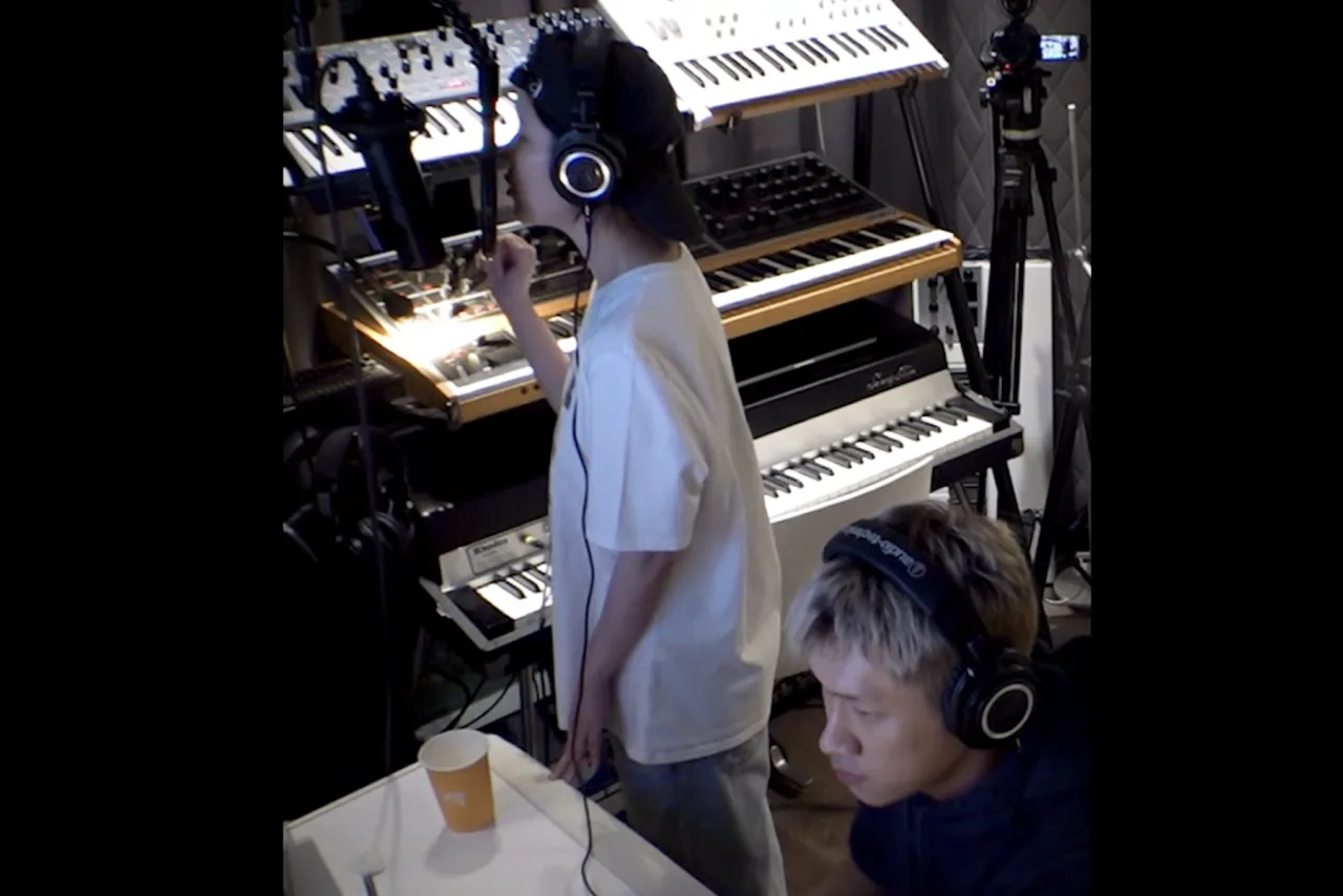 Crush e IU no estúdio, frente a microfones, enquanto a palavra “seesaw” aparece em destaque na tela