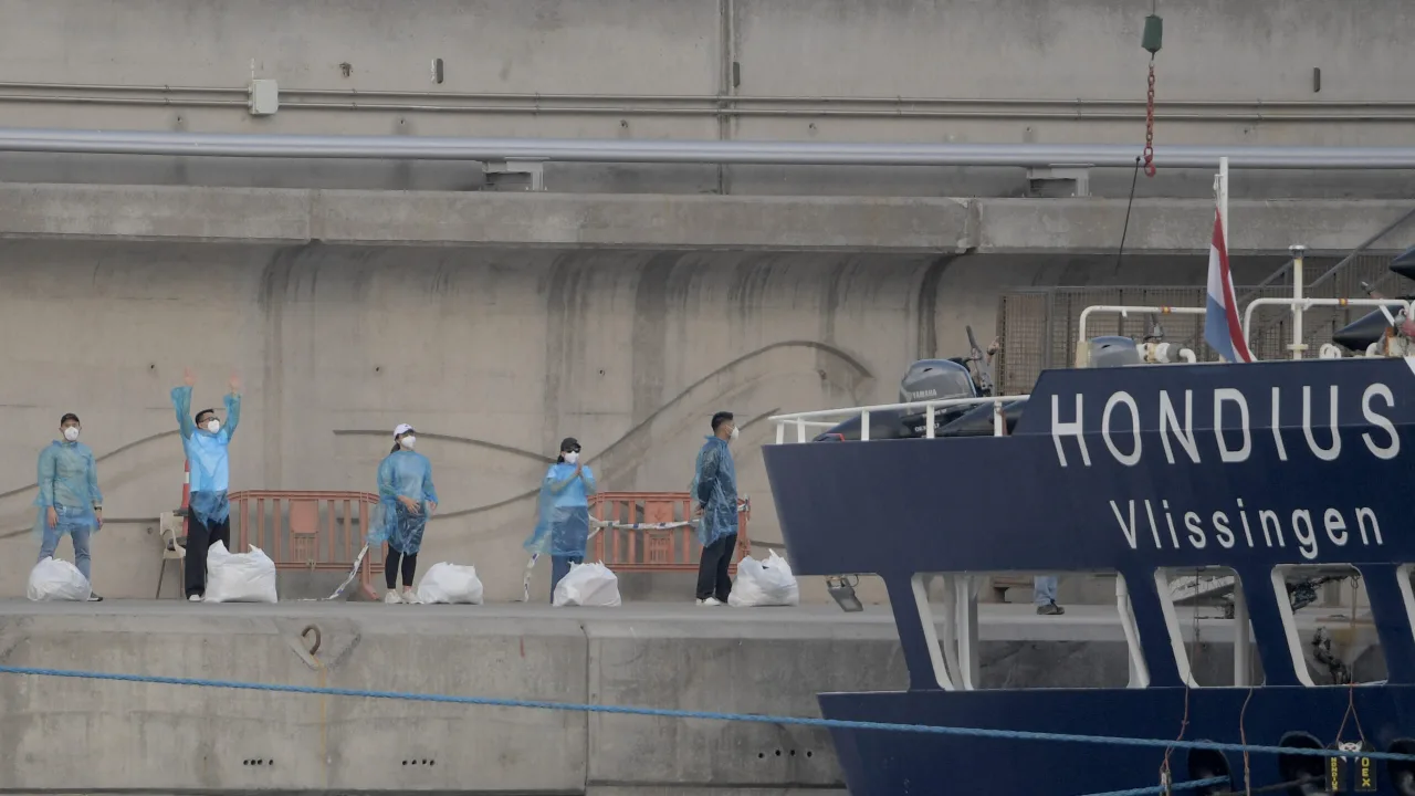 Profissionais em trajes hazmat brancos manuseiam macas de biocontenção seladas em uma unidade de isolamento médico