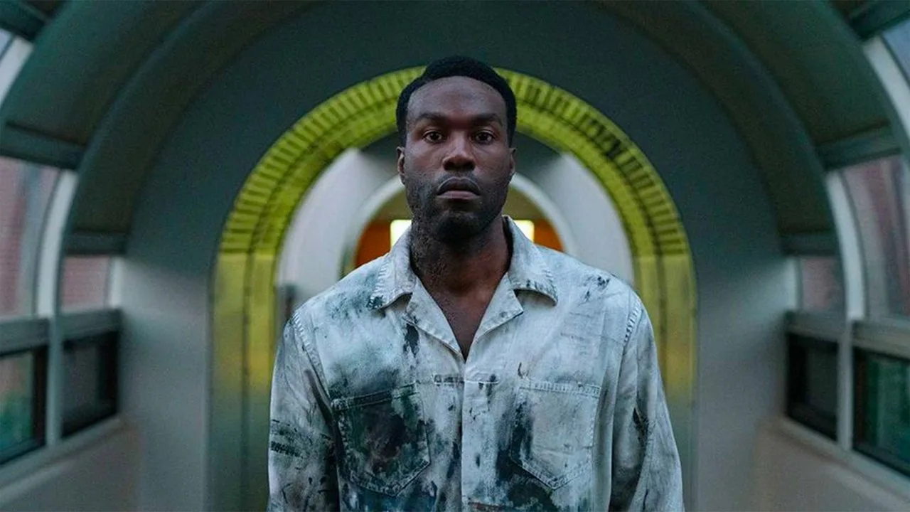 Jovem em camiseta de Candyman levanta halteres, ao lado de pipoca, poster da capa do filme e cronômetro de pulso
