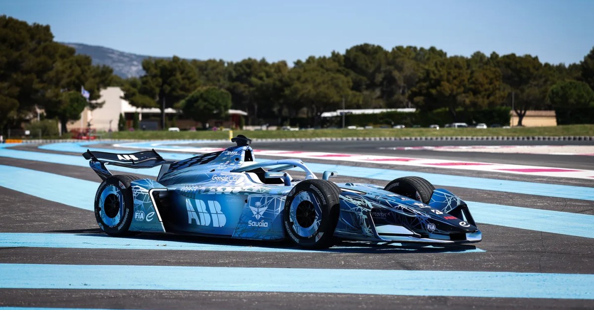 Atleta em roupa esportiva segurando garrafa d'água, ao fundo tela exibindo carros elétricos da Formula E