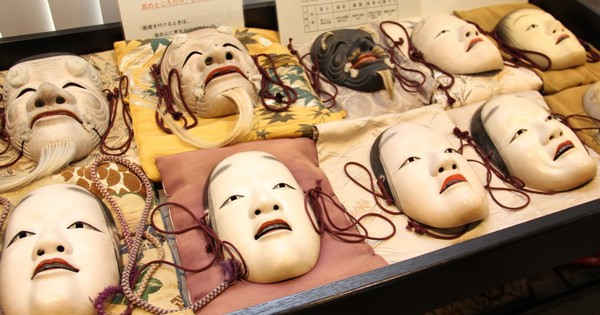 Um praticante de Noh em traje tradicional, realizando movimentos de kata sobre um tatame, ao lado de halteres e um cronômetro